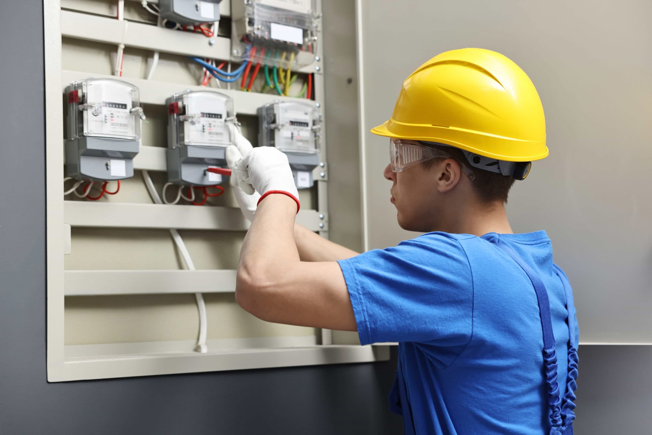 A focused electrician in safety gear performing a residential electrical inspection and electrical panel upgrade maintenance in South Florida.
