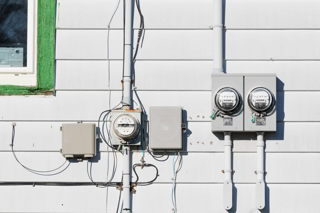 Interlock Kit vs. Transfer Switch: Best Generator Setup Guide 3 Exterior wall of a house featuring a residential electrical meter installation alongside multi-unit electric meters and outdoor utility boxes in Columbus, Ohio.